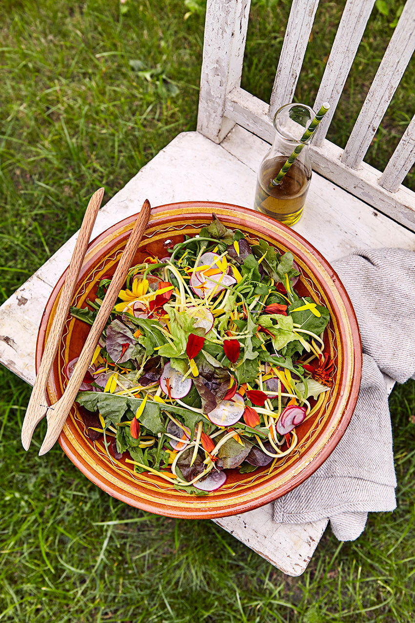 En skål med sallad står på en stol på en gräsmatta.