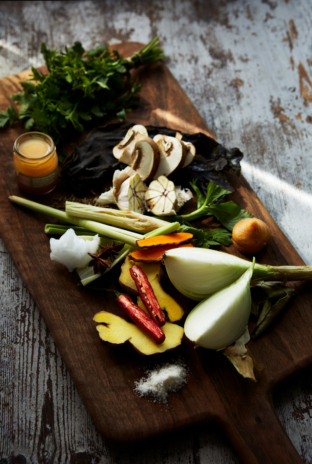 grönsaker ligger på en skärbräda, ljsuet är dovt och sipprar in genom en gardin.